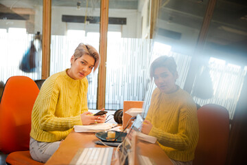 Obraz premium Portrait of young woman working at desk, smiling