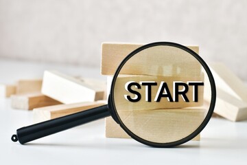 START. Magnifying glass with text START on a wooden blocks on a white table. Business and new year concept. Copy space. New year.