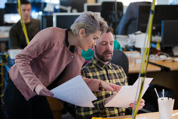 Two colleagues discussing paperwork in office