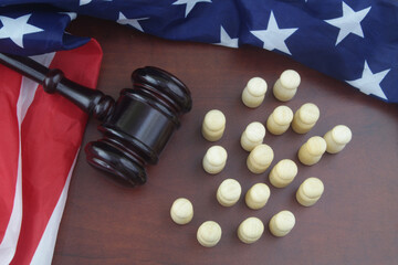 Wooden figures of people, United States flag and judge gavel om table.