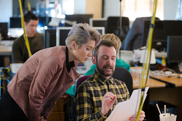Two colleagues discussing paperwork in office