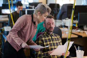 Two colleagues discussing paperwork in office