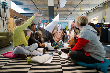 Team sitting on office floor, discussing paperwork