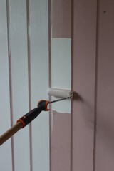 Roller brush painting. Painting wooden walls with white color. Home renovation concept. Worker painting on surface. 
