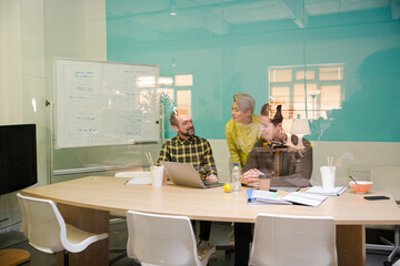 Three colleagues working at computer in conference room