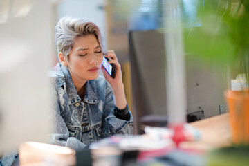 Young woman talking on cell phone in office