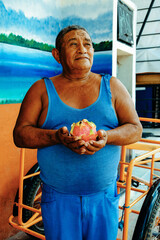 Thoughtful senior male fruit vendor selling dragon fruit at market