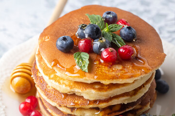 Healthy summer breakfast, homemade classic american pancakes with fresh fruit and honey, morning light gray stone background copy space top view