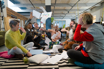 Team sitting on office floor, discussing paperwork