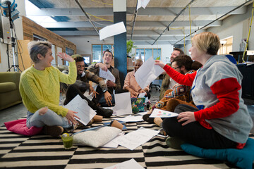 Team sitting on office floor, discussing paperwork