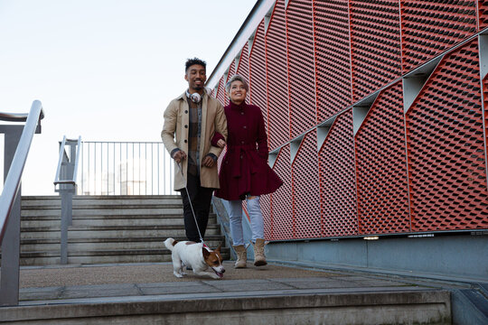 Smiling Young Couple Walking Dog Down Urban, Modern Stairs