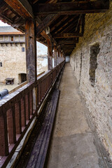 Fototapeta na wymiar Medieval old balcony with railing and wooden ceiling in long perspective.