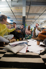 Team sitting on office floor, discussing paperwork