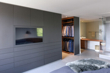 Spacious bedroom with a big black dresser and a television