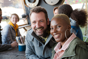Portrait of smiling couple dining with friends at restaurant outdoor patio