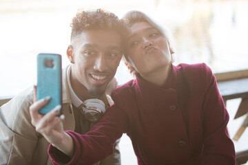 Playful young couple taking selfie with camera phone