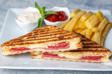 Turkish toast, mixed toast with cheddar cheese, sausage and ham, with fried potatoes (Turkish name; Karisik tost)