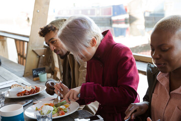 Portrait of smiling friends eating at restaurant outdoor patio