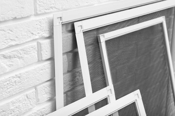 Set of window screens near white brick wall, closeup