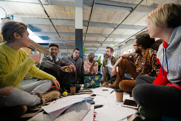 Team sitting on office floor, discussing paperwork