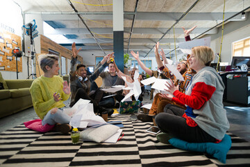 Team sitting on office floor, discussing paperwork