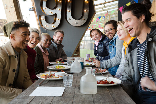 Portrait Of Smiling Friends Eating At Restaurant Outdoor Patio