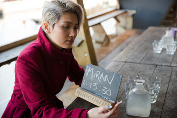 Fototapeta na wymiar Woman sitting at restaurant table, using smartphone
