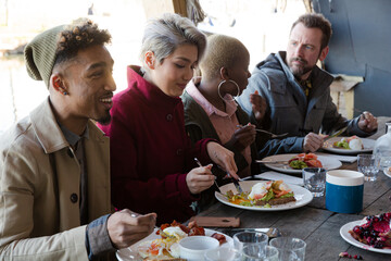 Portrait of smiling friends eating at restaurant outdoor patio