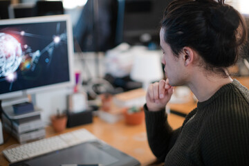 Smiling young man with long hair, working at computer