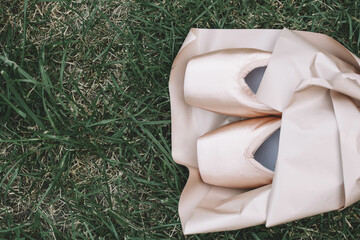 New ballet shoes, pointe shoes lie on a green background. Packaged as a bouquet of flowers. Dancing as an art form
