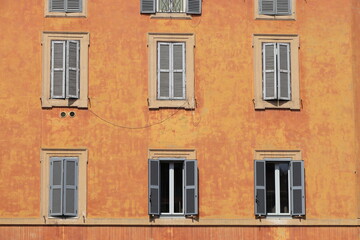 Fototapeta na wymiar Colorful Warm Orange Brown Building Facade with Grey Shutters in Rome, Italy