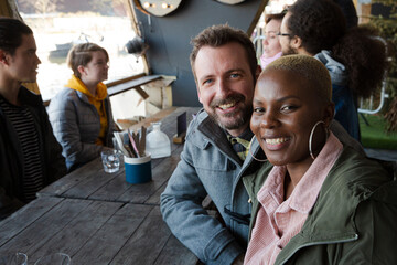 Obraz premium Portrait of smiling couple dining with friends at restaurant outdoor patio