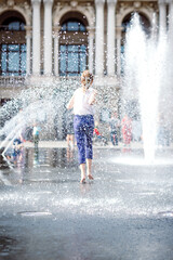 The girl runs on the fountain. 