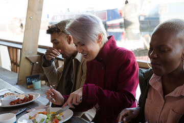 Portrait of smiling friends eating at restaurant outdoor patio