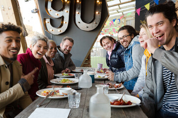 Portrait of smiling friends eating at restaurant outdoor patio