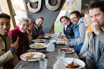 Portrait of smiling friends eating at restaurant outdoor patio