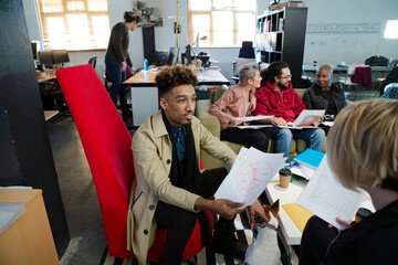 Colleagues discussing paperwork in office