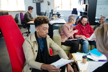 Colleagues discussing paperwork in office