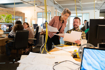 Obraz premium Man and woman discussing paperwork at desk