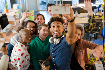 Team taking group selfie with smartphone in office