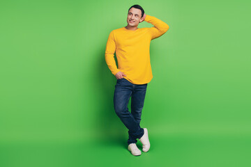 Fototapeta na wymiar Portrait of handsome positive guy hand pocket touch head on green background