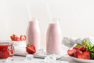 Traditional ayurvedic healthy Indian strawberry lassi or milkshake in bottles on a white background.