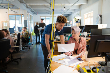 Man and woman discussing paperwork at desk