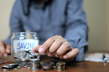 Asian businessman in gray shirt stacking coins and categorizing them to count savings. Financial and accounting concept.