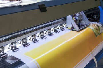 Large format inkjet printer machine working on vinyl paper in workplace