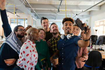 Team talking group selfie with smartphone in office