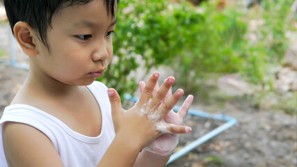 Asian cute child boy washing hands by soap foam with cute face. Kid cleaning hand outdoor. Concept of healthy, health care, covid 19 or corona virus prevention.