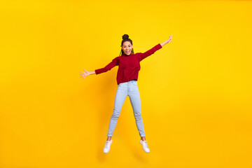Fototapeta na wymiar Full length photo of adorable sweet dark skin lady wear red pullover smiling jumping high isolated yellow color background