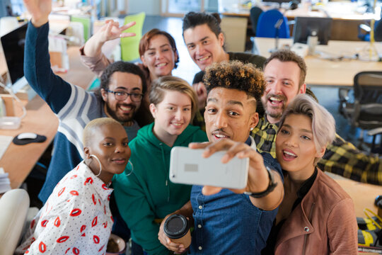 Team talking group selfie with smartphone in office