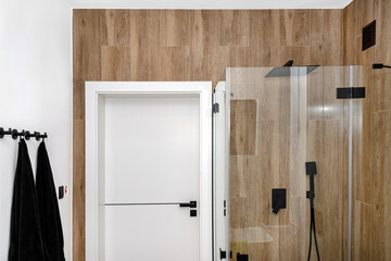 A modern bathroom with a closed shower door, lined with ceramic tiles imitating wood.